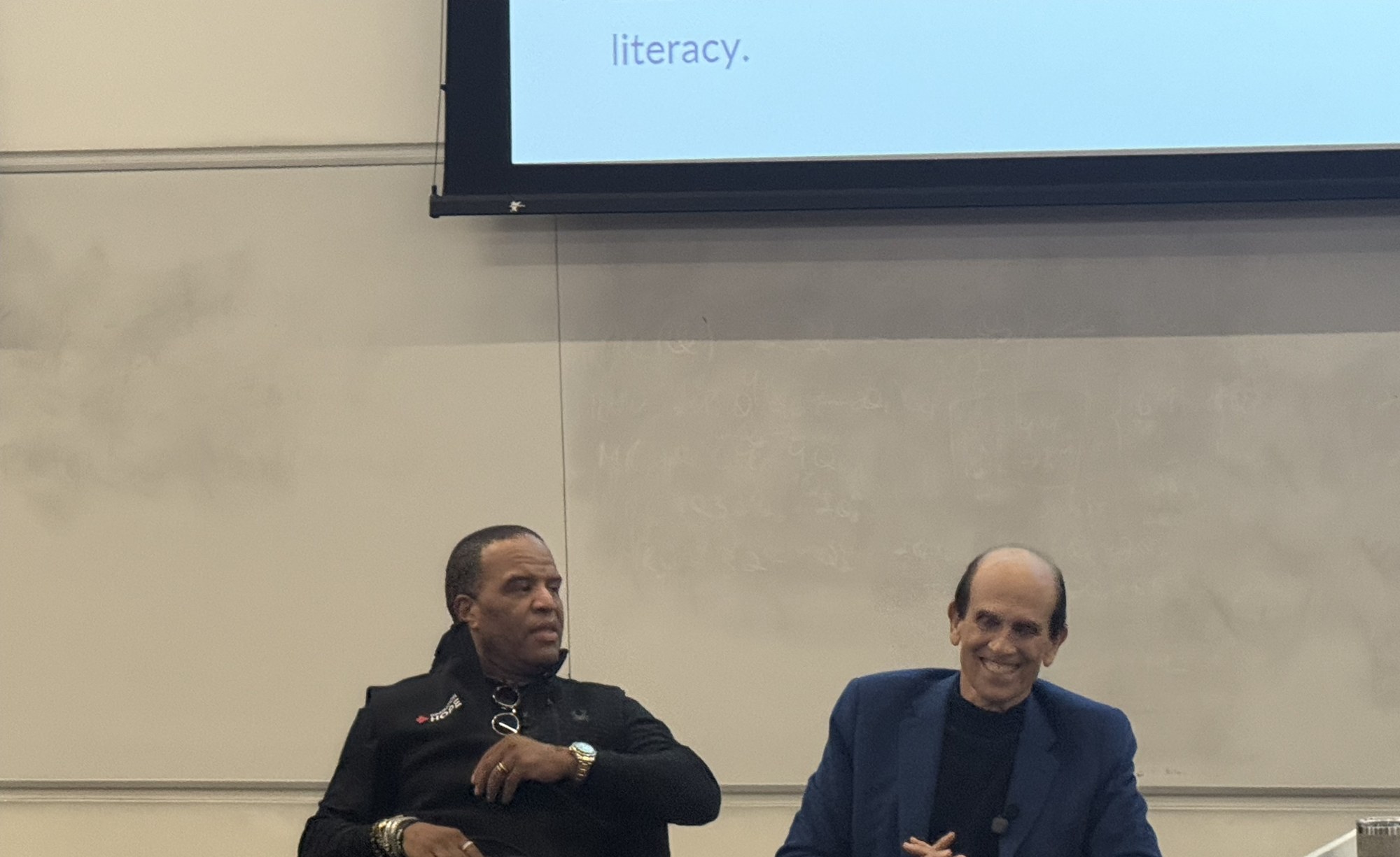 Michael Milken smiling as John Hope Bryant looks on during the USC fireside chat